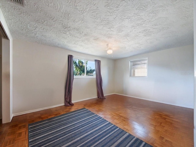 unfurnished room with baseboards, visible vents, and a textured ceiling