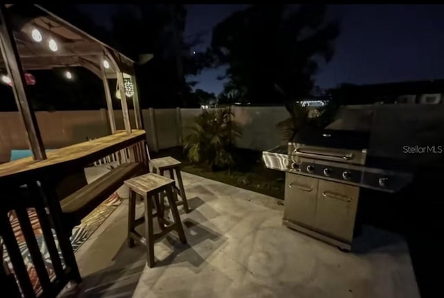 patio at twilight with fence and outdoor dry bar