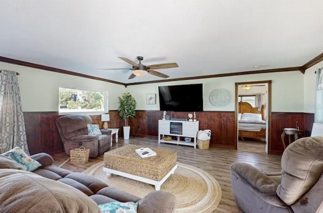 living area featuring wainscoting, a wealth of natural light, a ceiling fan, and wood finished floors