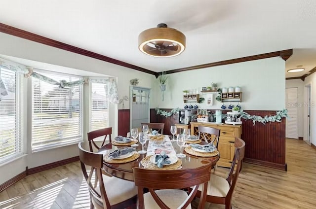 dining room featuring light wood-style flooring, a ceiling fan, baseboards, and ornamental molding
