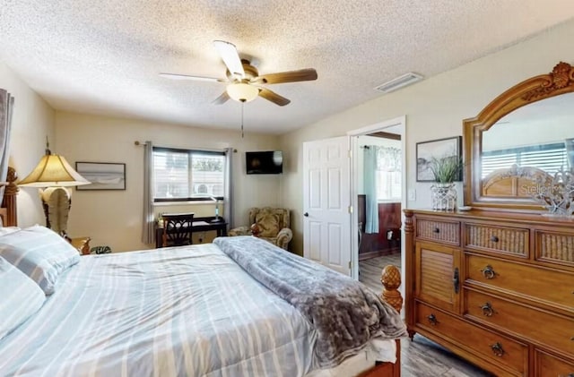 bedroom with a ceiling fan, a textured ceiling, and visible vents