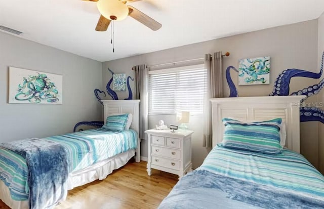 bedroom with a ceiling fan, wood finished floors, and visible vents