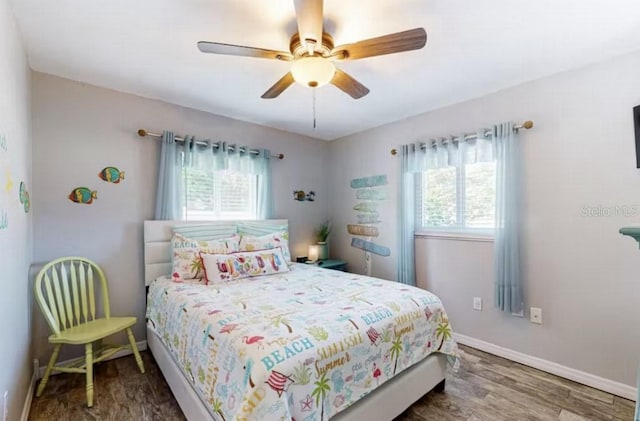 bedroom with wood finished floors, a ceiling fan, baseboards, and multiple windows