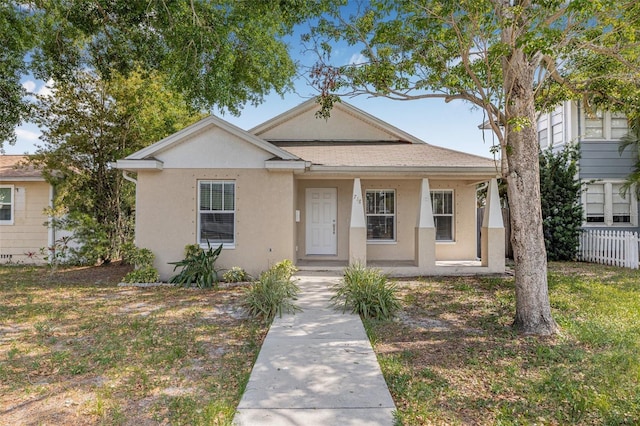 bungalow-style house with stucco siding, fence, and covered porch