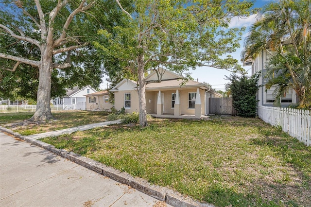 bungalow-style house featuring stucco siding, a front lawn, and fence