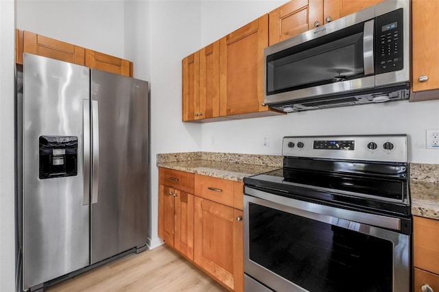kitchen with brown cabinetry, stainless steel appliances, and light wood-style floors