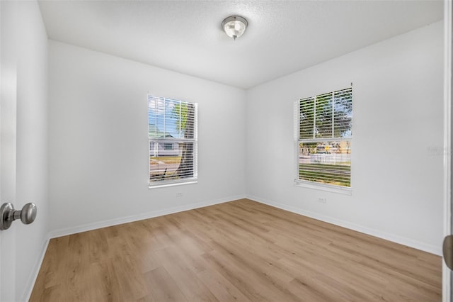 empty room with light wood-style floors, a healthy amount of sunlight, and baseboards