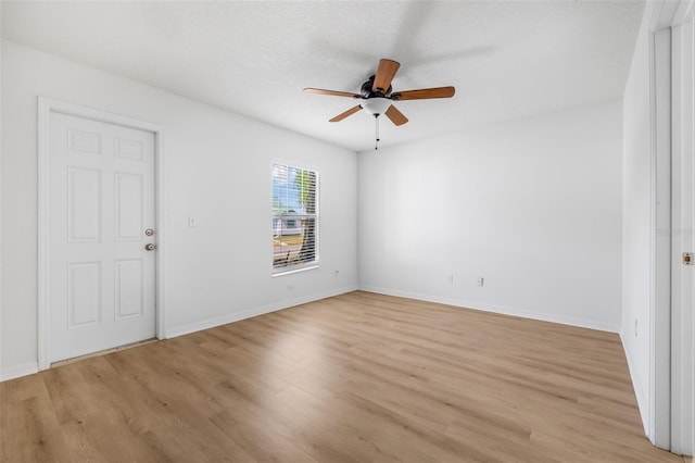 spare room featuring light wood-style floors, baseboards, and ceiling fan