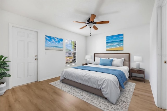 bedroom with light wood finished floors, baseboards, and ceiling fan