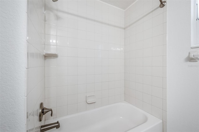 bathroom with a textured wall and bathtub / shower combination