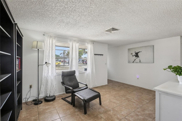 living area featuring light tile patterned flooring, a textured ceiling, and visible vents