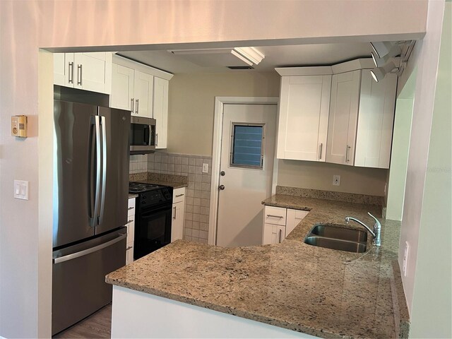 9825 41st St N, Pinellas Park, FL 33782 - kitchen featuring a peninsula, light stone countertops, white cabinetry, a sink, and appliances with stainless steel finishes