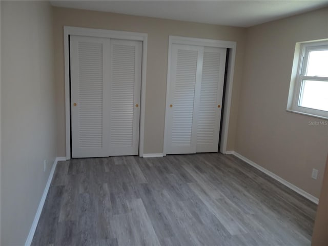 9825 41st St N Unit 9825, Pinellas Park, FL 33782 - unfurnished bedroom with baseboards, multiple closets, and wood finished floors