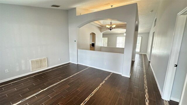 28818 Midnight Star Loop, Wesley Chapel, FL 33543 - empty room with arched walkways, a chandelier, dark wood-type flooring, and baseboards