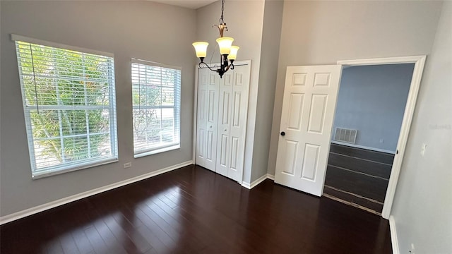 28818 Midnight Star Loop, Wesley Chapel, FL 33543 - unfurnished dining area featuring a chandelier, baseboards, dark wood-style floors, and a high ceiling