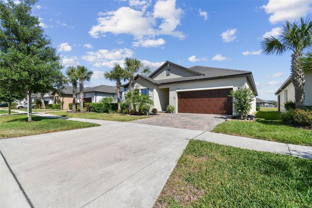 ranch-style house with a garage, stucco siding, a front yard, and decorative driveway