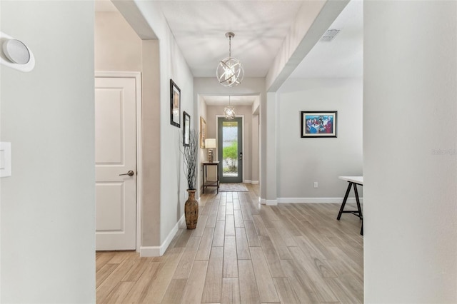 foyer featuring visible vents, light wood finished floors, baseboards, and an inviting chandelier