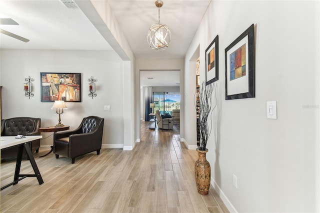 entryway featuring light wood-type flooring, baseboards, visible vents, and ceiling fan with notable chandelier