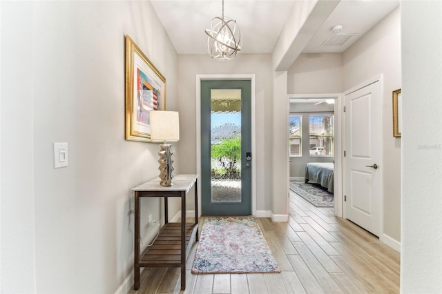 entrance foyer featuring baseboards, a chandelier, and light wood finished floors