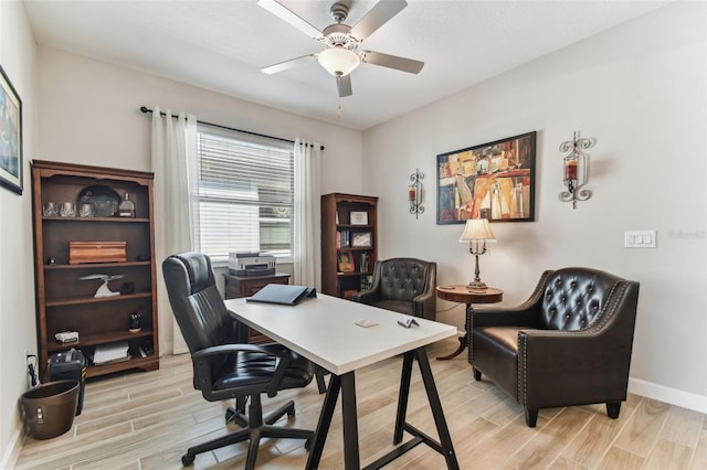 office space with ceiling fan, baseboards, and light wood-style floors