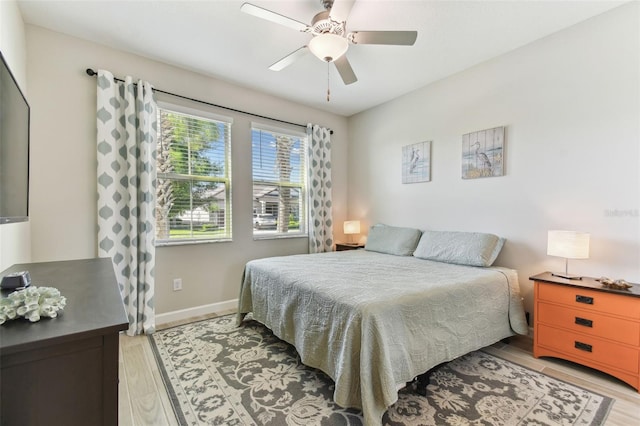 bedroom featuring light wood finished floors, baseboards, and ceiling fan