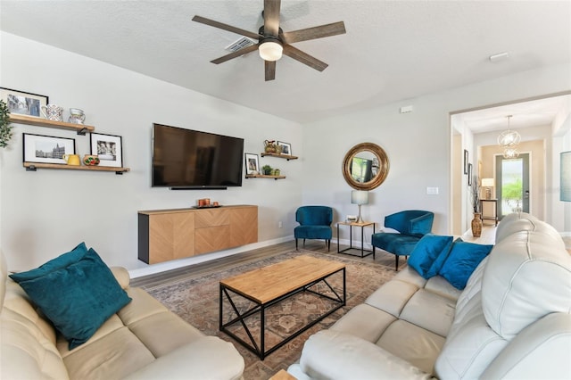 living room with visible vents, baseboards, and ceiling fan with notable chandelier