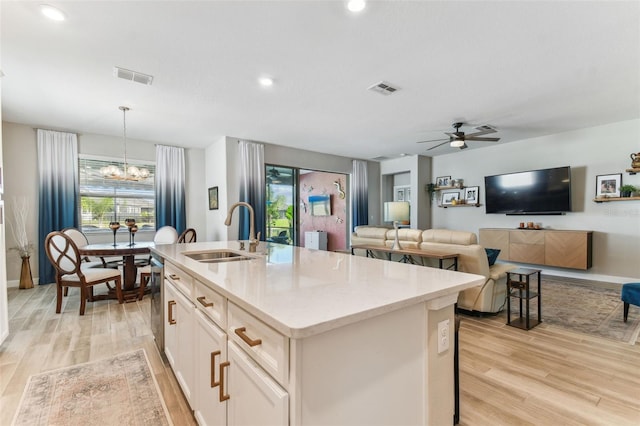 kitchen with an island with sink, visible vents, a sink, and light wood-style floors