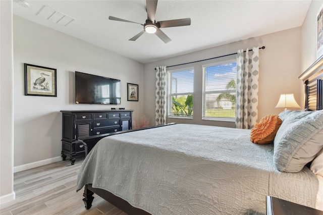 bedroom featuring visible vents, baseboards, wood finished floors, and multiple windows