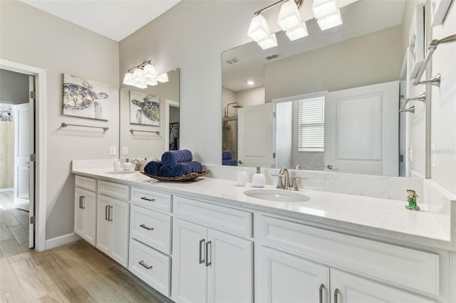 bathroom with wood finished floors, visible vents, a sink, and double vanity