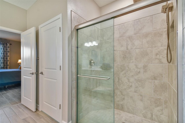 ensuite bathroom with baseboards, wood finished floors, a stall shower, and ensuite bathroom