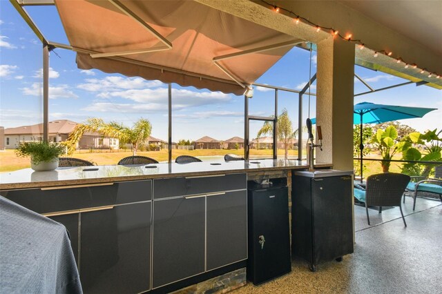 view of patio / terrace with outdoor dry bar, a residential view, and glass enclosure