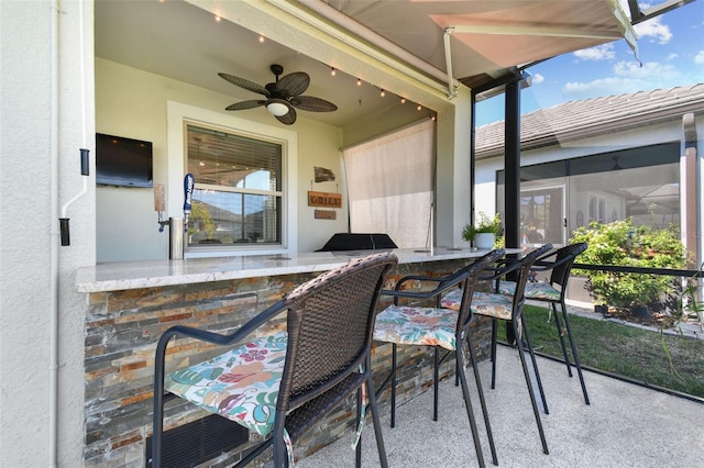 view of patio featuring exterior bar and a ceiling fan