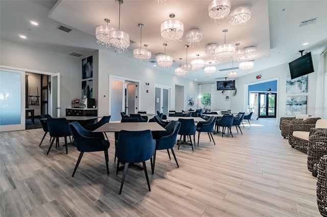 dining space featuring a chandelier, light wood-style flooring, and visible vents