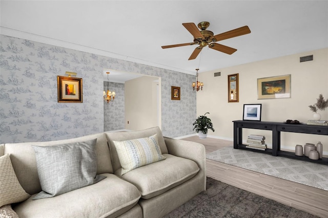 living area featuring wood finished floors, a chandelier, baseboards, wallpapered walls, and ceiling fan