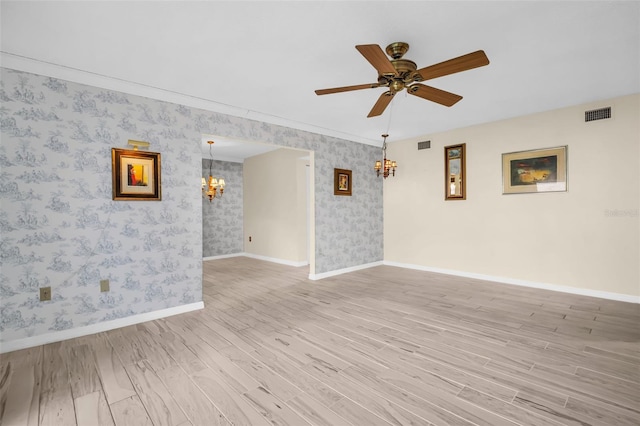 spare room featuring a chandelier, light wood-style flooring, wallpapered walls, baseboards, and ceiling fan