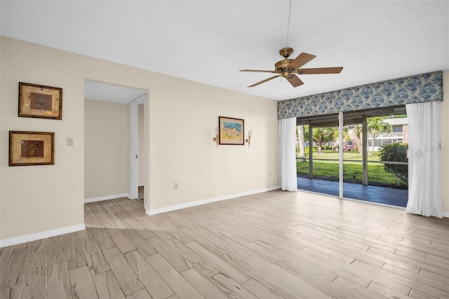 spare room with a ceiling fan, light wood-type flooring, and baseboards