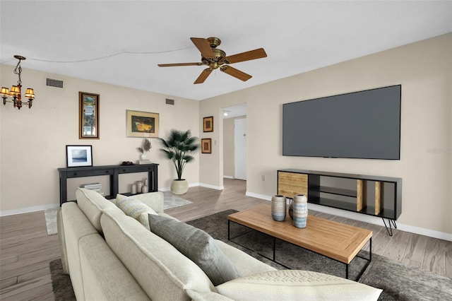 living area with a chandelier, wood finished floors, a ceiling fan, and baseboards
