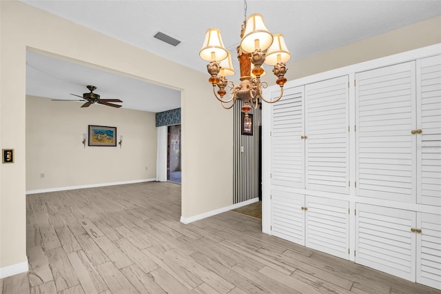 unfurnished dining area featuring baseboards, a chandelier, ceiling fan, and wood finished floors