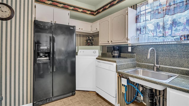 kitchen featuring black refrigerator with ice dispenser, dishwasher, washer / dryer, a sink, and dark countertops