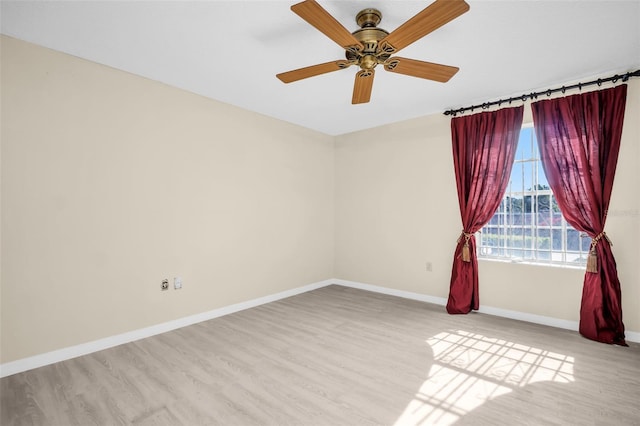 spare room featuring wood finished floors, baseboards, and a ceiling fan