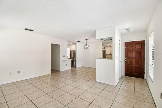 spare room with baseboards, visible vents, and light tile patterned flooring