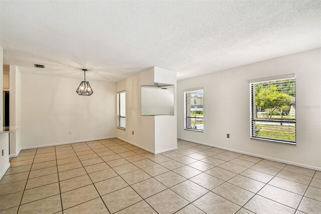 unfurnished room with light tile patterned floors, a textured ceiling, visible vents, baseboards, and a notable chandelier