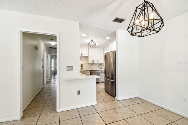 kitchen with light tile patterned floors, an inviting chandelier, appliances with stainless steel finishes, and light countertops