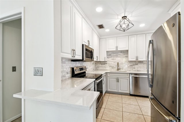 kitchen with a sink, visible vents, a peninsula, backsplash, and appliances with stainless steel finishes