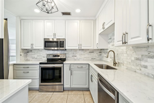 kitchen with light tile patterned floors, a sink, appliances with stainless steel finishes, and white cabinetry