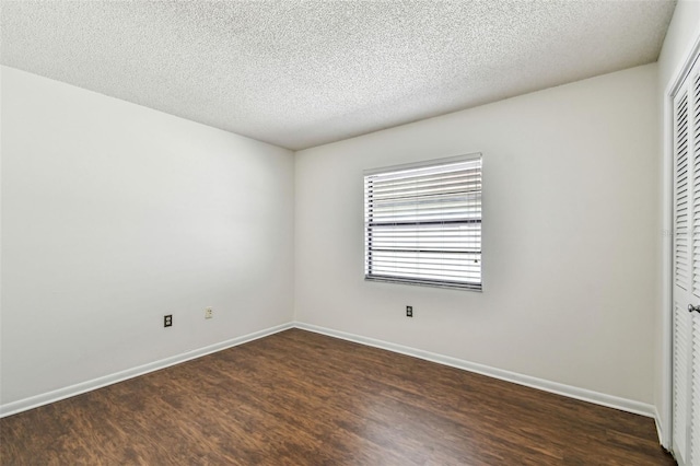 unfurnished bedroom featuring dark wood-style floors, a closet, a textured ceiling, and baseboards
