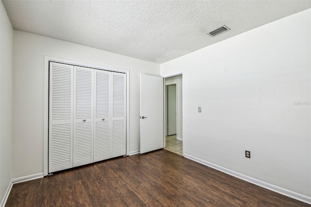 unfurnished bedroom featuring a closet, visible vents, wood finished floors, and baseboards