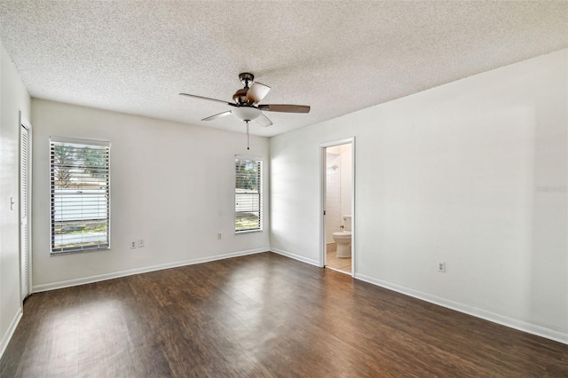 empty room featuring baseboards, a ceiling fan, a textured ceiling, and dark wood-style flooring