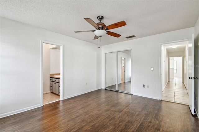 unfurnished bedroom with wood finished floors, baseboards, visible vents, and a closet