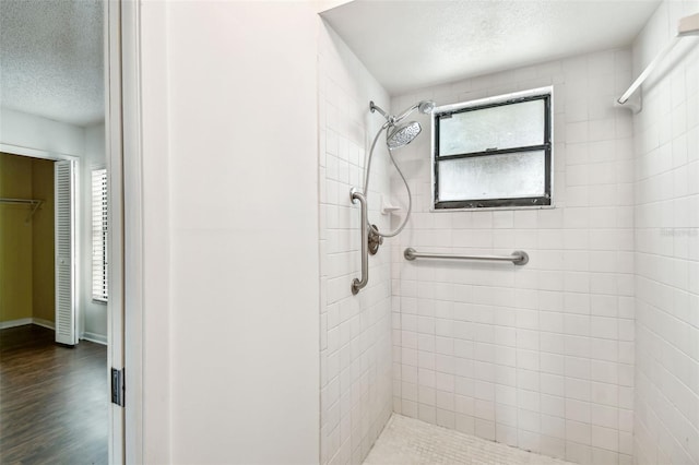 bathroom with tiled shower, a textured ceiling, and wood finished floors